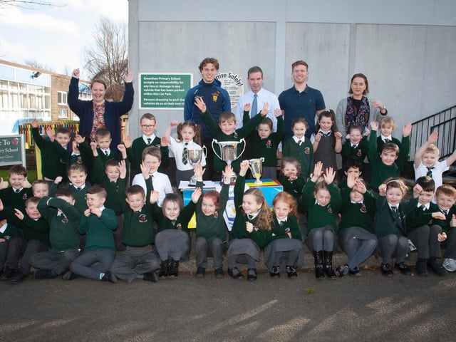 Primary 2 pupils and staff at Greenhaw Primary Schoolwith Brian Ogs player Donnacha Gilmore and the trophies won last season by the local club. (Photos: Jim McCafferty Photography)