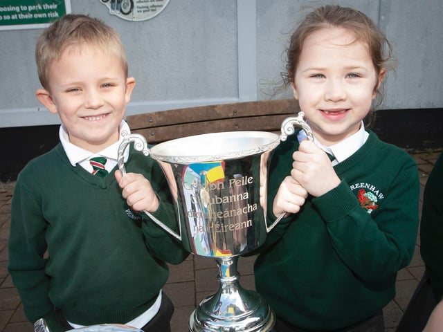 Charlie Harkin and Aoibheann Doherty proudly hold the All-Ireland Intermediate Club Championship trophy, the Kieran O'Sullivan Cup, at Greenhaw Primary School. (Photo: Jim McCafferty)