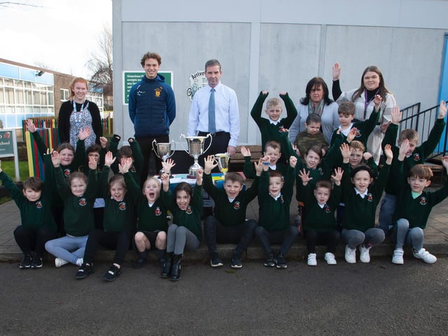Primary 3 pupils at Greenhaw Primary School pictured with Brian Ogs player Donncha Gilmore and the trophies won last season by the local club. Included centre is Mr. Sean McLaughlin, Principal.