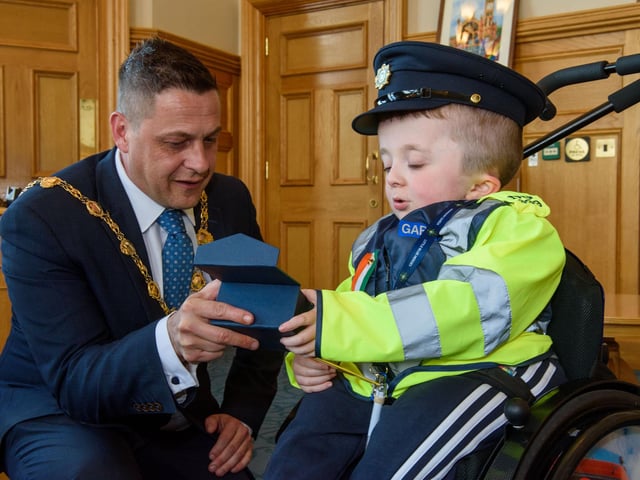 Jack Beattie from Donegal who has Osteogenesis Imperfacta or Brittle Bone Disease pictured during a reception held for him by Alderman Graham Warke, Mayor of Derry City and Strabane District Council. The honorary Garda also met with members of the PSNI who presented him with a certificate of recognition and the PSNI crest. Jack also made his first arrest in the North when he put the handcuffs on his dad Kevin.  Picture Martin McKeown. 30.03.22