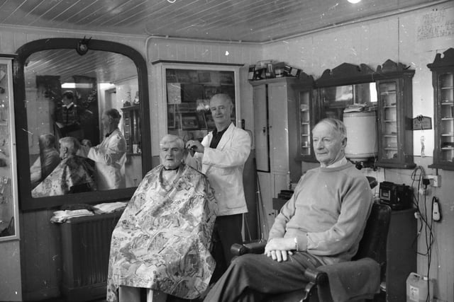 Mr. Paddy Harkin attending to customers at his barber shop in Moville.
