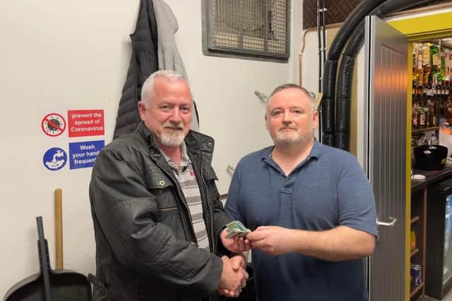 Danny Larkin, manager of Murphy's bar, presenting £300 to Raymond Brady, Dungiven Men's Shed. Danny and friends raised the money by eating fermented herring in front of a live audience.