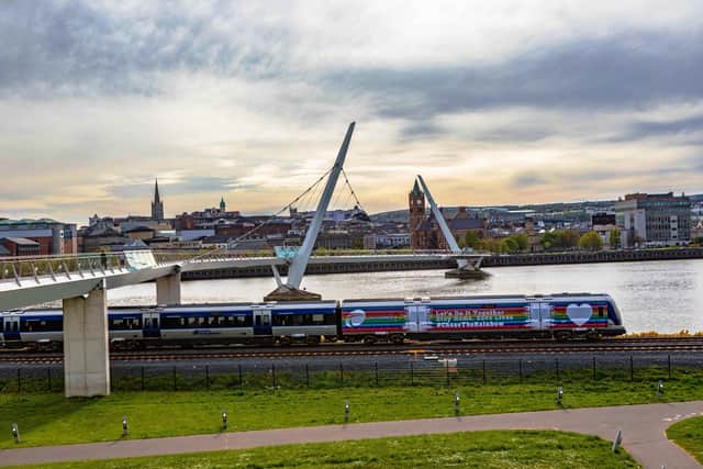 The Derry to Belfast train passes the city’s iconic Peace Bridge at Ebrington. Photo: Tony Monaghan.