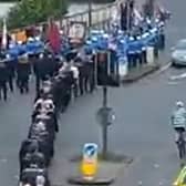 The cyclist makes his way onto Craigavon bridge passing by  the Loyal Order march.