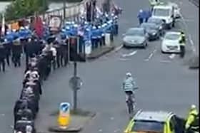 The cyclist makes his way onto Craigavon bridge passing by  the Loyal Order march.