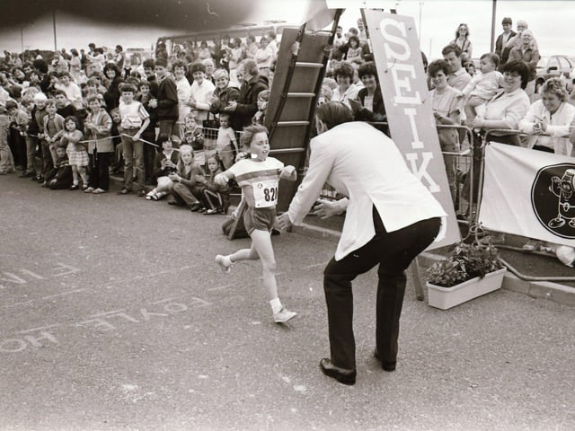 Michelle Deeney, the youngest runner, is welcomed across the line by Dr Tom McGinley.