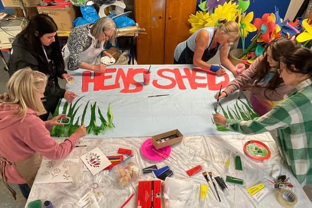 The Creggan Hens' Shed preparing a banner for the parade.