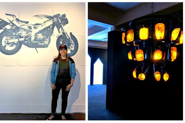Brigid Mulligan alongside a life-size cyanotype print of her late brother’s motorcycle, and  her ‘Chandelier’ light sculpture assembled from recycled motorcycle indicators at Artlink Fort Dunree.