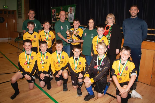The late Sean O'Kane's mum Breige and dad Feargal present the winning trophy to St. John's PS A team at St. Joseph's Boys School on Tuesday afternoon.