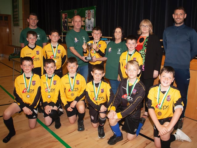 The late Sean O'Kane's mum Breige and dad Feargal present the winning trophy to St. John's PS A team at St. Joseph's Boys School on Tuesday afternoon.