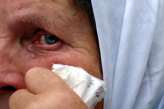 A Muslim Bosnian woman cries as a convoy carrying the remains of 610 Muslim Bosnians arrives at the former battery factory in Potocari, near eastern Bosnian town of Srebrenica, 09 July 2005. The victims aged between 14 and 75 years were later laid to rest in a memorial cemetary in Potocari, during ceremonies commemorating the 10th anniversary of the Srebrenica massacre, in which some 8,000 Muslim Bosnians were killed. (JOE KLAMAR/AFP via Getty Images)