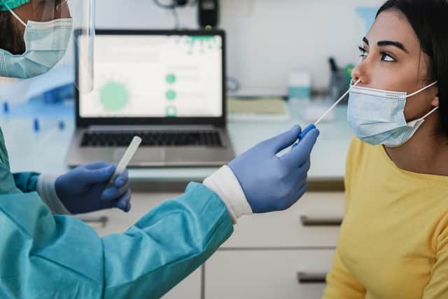 Doctor making swab nasal test to young woman in medical clinic for possible coronavirus infection.