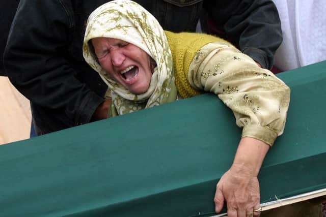 A Bosnian Muslim woman, survivor of Srebrenica massacre in 1995, cries as she holds the casket of her relative at the Potocari-Srebrenica Memorial Center, near the eastern Bosnian town of Srebrenica 11 July 2005, where 610 victims of the 1995 Srebrenica massacre aged between 14 and 75 years are laid to rest.  (Photo by ELVIS BARUKCIC/AFP via Getty Images)
