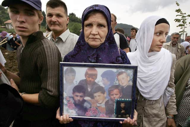 POTOCARI, BOSNIA AND HERCEGOVINA:  A Bosnian Muslim woman carries a picture of children, victums of the 1995 Srebrenica massacre (DIMITAR DILKOFF/AFP via Getty Images)