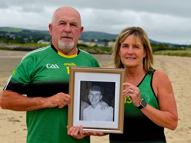 Gerry and Moira ODonnell pictured with a photograph of their late son Aodhán, a member of Na Magha hurling club, at a joint fundraising event with Waves for Mental Health held at Ludden Beach on Saturday and Sunday morning last. The ODonnell family have raised over £100,000 for mental health charities and organisations in the city in Aodháns memory. Photograph: George Sweeney.  DER2228GS  001