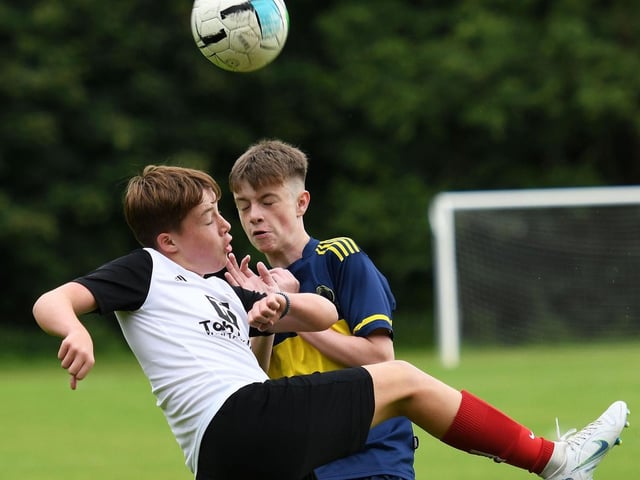 Hillsborough Boys defender Charlie Bland clears his lines under pressure from Don Boscos under-14's forward Matthew Burnside.