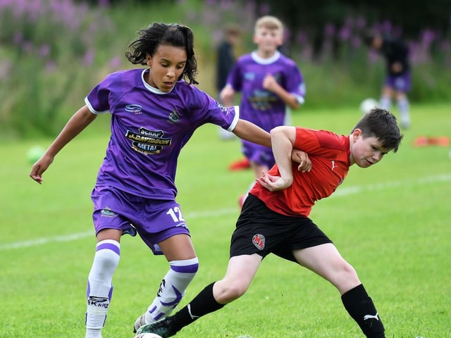 Altrincham F.C. under-12's forward Dexter Francis holds off this challenge from a Newhill F.C. defender.