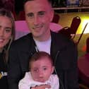 Aaron holding his baby daughter Pixie alongside his partner Ellen.