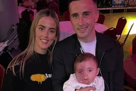 Aaron holding his baby daughter Pixie alongside his partner Ellen.