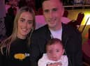 Aaron holding his baby daughter Pixie alongside his partner Ellen.