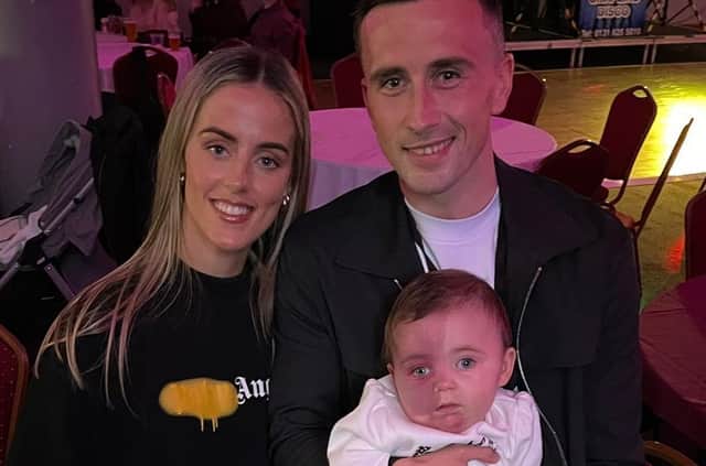 Aaron holding his baby daughter Pixie alongside his partner Ellen.