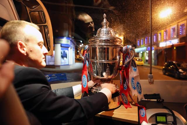 Former Derry City kitman, Aidy Canning places the FAI Cup proudly on display on the Derry City team coach after winning the 2012 cup final at the Aviva Stadium.