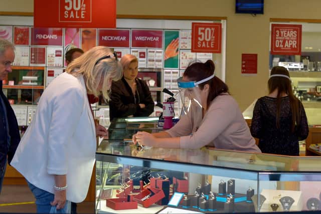 A shop assistant in a city centre jewellers wearing a face shield in early 2020. DER2027GS - 020