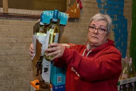 Proprietor Ruby Butler inspects the water damage to stock in the storeroom of O’Kane’s Liquor Store in Shantallow. DER2118GS – 006