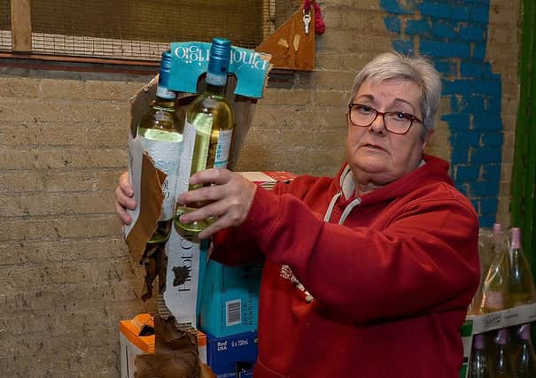 Proprietor Ruby Butler inspects the water damage to stock in the storeroom of O’Kane’s Liquor Store in Shantallow. DER2118GS – 006