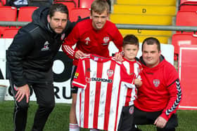 Derry City manager Ruaidhri Higgins and vice captain Ciaron Harkin present a signed Derry jersey to five year old Caleb Toland, who underwent major brain surgery last month, and his father Richie. Photographs by Kevin Moore
