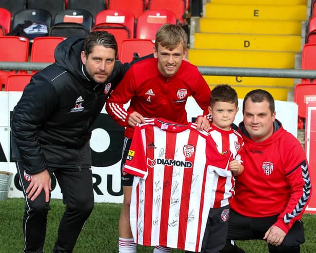 Derry City manager Ruaidhri Higgins and vice captain Ciaron Harkin present a signed Derry jersey to five year old Caleb Toland, who underwent major brain surgery last month, and his father Richie. Photographs by Kevin Moore