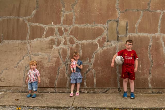 Nine-year-old Tiernan Long from Inch Island with his younger siblings five-year-old Samarah and two-year-old Matthew outside their Mica damaged home. (Photo: Brendan Diver)