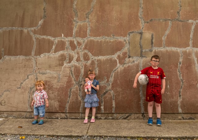 Nine-year-old Tiernan Long from Inch Island with his younger siblings five-year-old Samarah and two-year-old Matthew outside their Mica damaged home. (Photo: Brendan Diver)