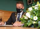 Derry City and Strabane District Council Mayor, Alderman Graham Warke, signs the Book of Condolence for Pat Hume in the Guildhall. Picture Martin McKeown. 03.09.21