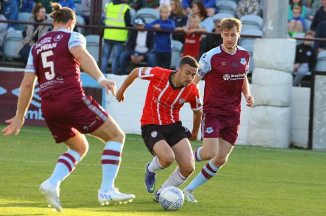 Derry City’s Michael Duffy skips in between Drogheda United defenders Keith Cowan (No 5) and Andrew Quinn.
