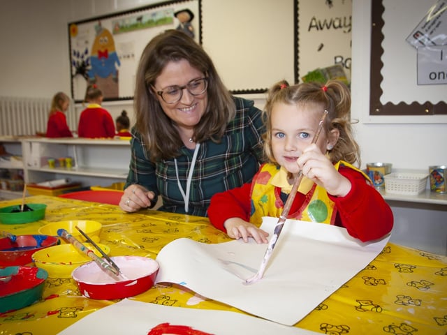 Young Alisha Kerrigan starts her painting under the watchful eye of Mrs. Catherine McCarron, Classroom Assistant.