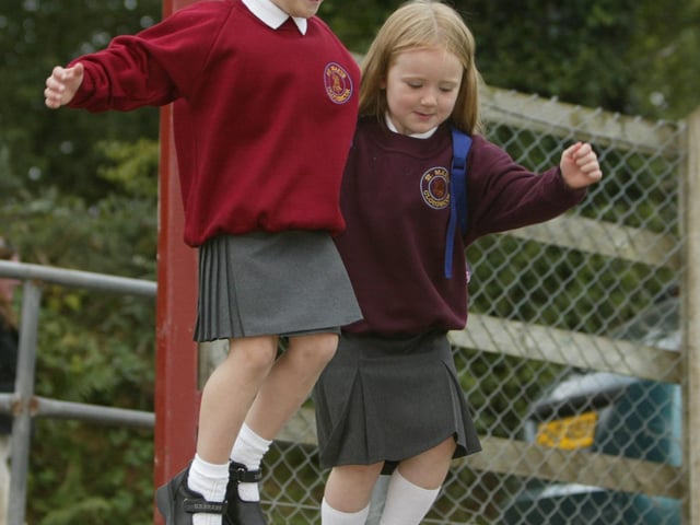 Chloe McCafferty and her friend Orlagh McCloskey jumping for joy as they go to St. mary's PS, Cloughcor for their first day at school. (0209JB65). pic. Joe Boland:20 YEARS ON: Pictures of Derry children starting primary 1 in September 2003