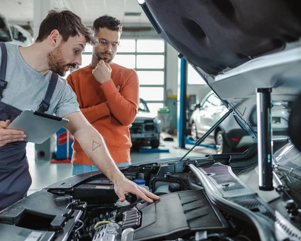 Auto mechanic explaining the problem to the customer while using digital tablet in a repair shop