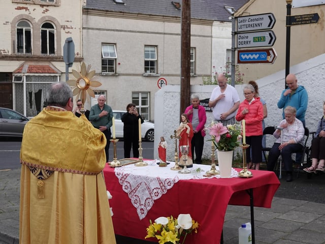 Father Bradley and parishioners pray at one of the altars along the route of the procession.
