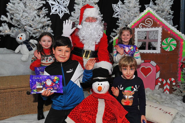 St Eithne’s Primary School P4 pupils Eadaoin, Saher, Harry and Portia from Mrs Coyle’s class pictured with Santa during his visit on Friday. Photo: George Sweeney. DER2250GS – 52