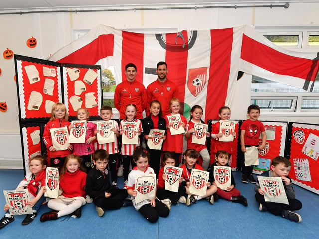 Pupils from Gaelscoil Eadain Mhoir pictured with Derry City’s Ciaran Coll and Pat Hoban during their visit to the school on Monday morning. Photo: George Sweeney