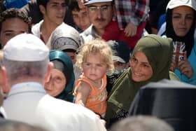 TOPSHOT - Pope Francis greets migrants and refugees at the Moria refugee camp on April 16, 2016 near the port of Mytilene, on the Greek island of Lesbos. Pope Francis received an emotional welcome today on the Greek island of Lesbos during a visit aimed at showing solidarity with migrants fleeing war and poverty.  Pope Francis, Orthodox Patriarch Bartholomew and Archbishop Jerome visit Lesbos today to turn the spotlight on Europe's controversial deal with Turkey to end an unprecedented refugee crisis.  AFP PHOTO POOL / FILIPPO MONTEFORTE (Photo by FILIPPO MONTEFORTE / POOL / AFP) (Photo by FILIPPO MONTEFORTE/POOL/AFP via Getty Images)