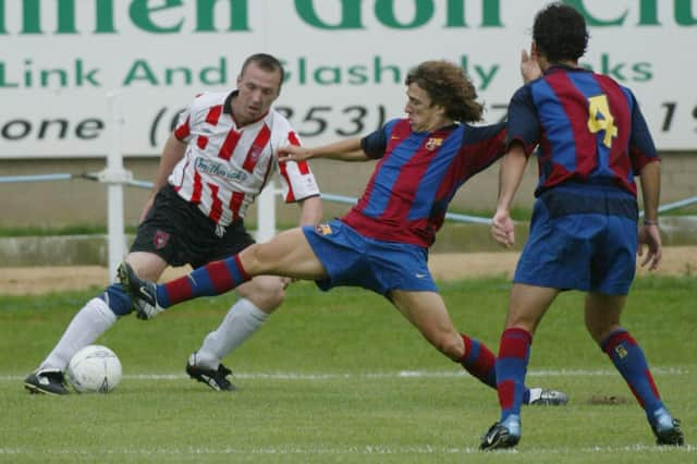 Carlos Puyol challenges Liam Coyle as Rafael Márquez looks on.