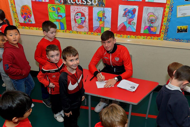 Derry City’s Liam Mullan signs autographs for pupils during a visit to Good Shepherd Primary School on Friday afternoon. Photo: George Sweeney. DER2247GS – 77