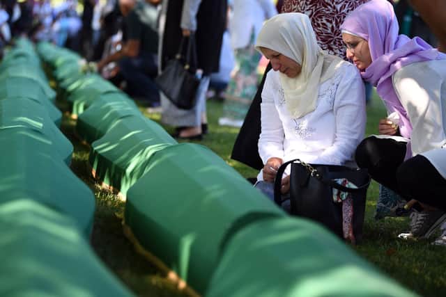 A Bosnian Muslim woman, a survivor of the 1995 Srebrenica massacre, mourns near the caskets containing remains of her relatives, at the memorial cemetery in the village of Potocari, near eastern Bosnian town of Srebrenica, on July 11, 2022. (Photo by ELVIS BARUKCIC / AFP) (Photo by ELVIS BARUKCIC/AFP via Getty Images)
