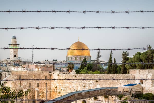 Jerusalem with the wall and the dome protected behind barbed wire at dusk