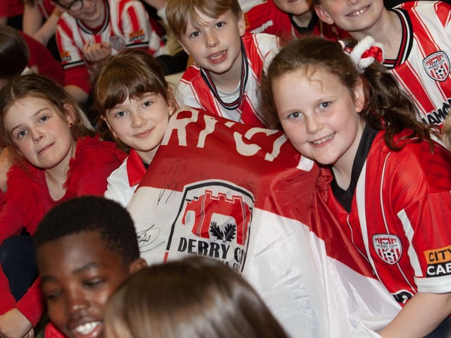 Hollybush PS pupils and ardent Derry City supporters Orla, Meadbh and Zoe holding their City flag.