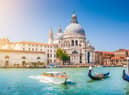 Beautiful view of traditional Gondola on Canal Grande with historic Basilica di Santa Maria della Salute in the background on a sunny day in Venice, Italy