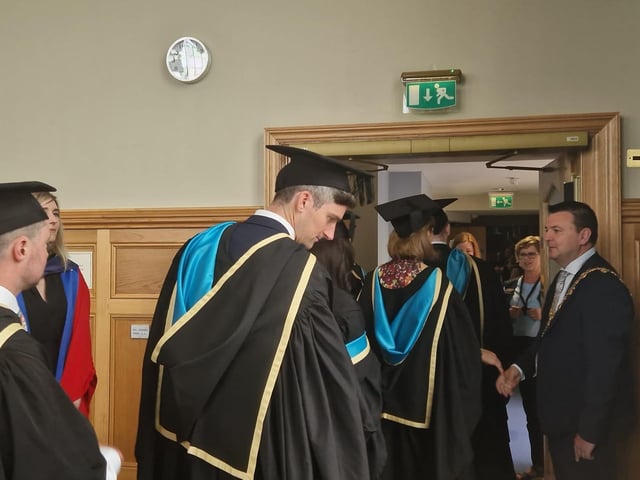 Graduates are congratulated by the Mayor of Derry & Strabane, Councillor Ruairí McHugh, as they make their way from the Council chamber to the Main Hall in the Guildhall to complete their graduation.