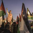 People raise flags and placards as they gather around a statue of late South African president Nelson Mandela to celebrate a landmark "genocide" case filed by South Africa against Israel at the International Court of Justice, in the occupied West Bank city of Ramallah on January 10, 2024. The ruling African National Congress (ANC) has long been a firm supporter of the Palestinian cause, often linking it to its own struggle against the white-minority government, which had cooperative relations with Israel. (Photo by MARCO LONGARI / AFP) (Photo by MARCO LONGARI/AFP via Getty Images)